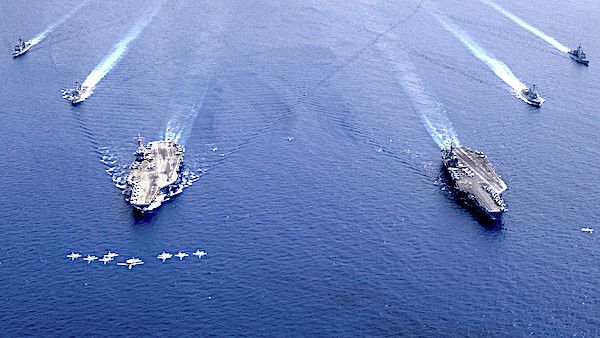 Aircraft fly in formation over the Nimitz Carrier Strike Force including the aircraft carriers USS Nimitz, right, and USS Ronald Reagan, as they conduct dual carrier operations in the South China Sea, July 6, 2020. (U.S. Navy photo by Mass Communication Specialist 3rd Class Keenan Daniels)