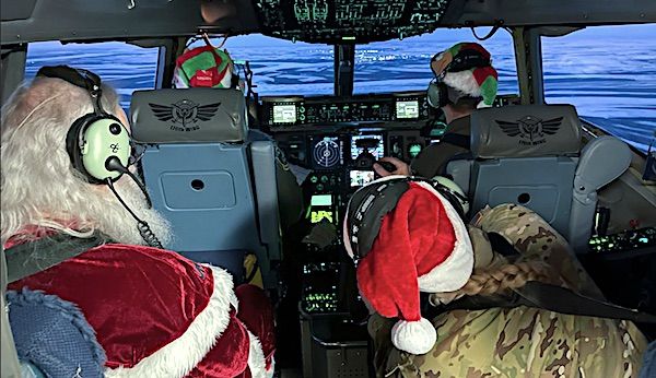 The 144th Airlift Squadron's favorite passenger, Santa Claus, and his helper elves gaze out the window of a 176th Wing C-17 Globemaster III aircraft on his way to deliver tidings of good cheer to the children of Scammon Bay during Operation Santa Claus Nov. 16, 2022. (Alaska National Guard photo by Staff Sgt. Annie Kilborn)