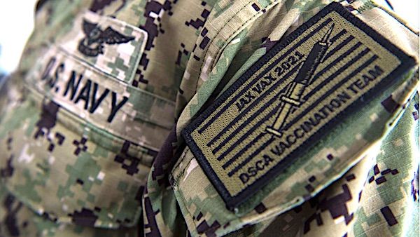 Yeoman 2nd Class Hunter Bourque, assigned to Navy Medicine Readiness and Training Command Jacksonville, models the command patch of the Jacksonville Vaccination Support Team while providing support at the Community Vaccination Center in Jacksonville, Florida, April 19, 2021. (U.S. Navy photo by Mass Communication Specialist 3rd Class Griffin Kersting)
