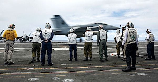 Military leaders from Colombia and Israel observe an F/A-18F Super Hornet assigned to the 